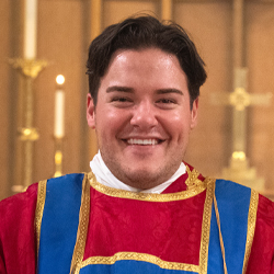 Headshot of Cam Walker, wearing a cassock and red and blue surplus