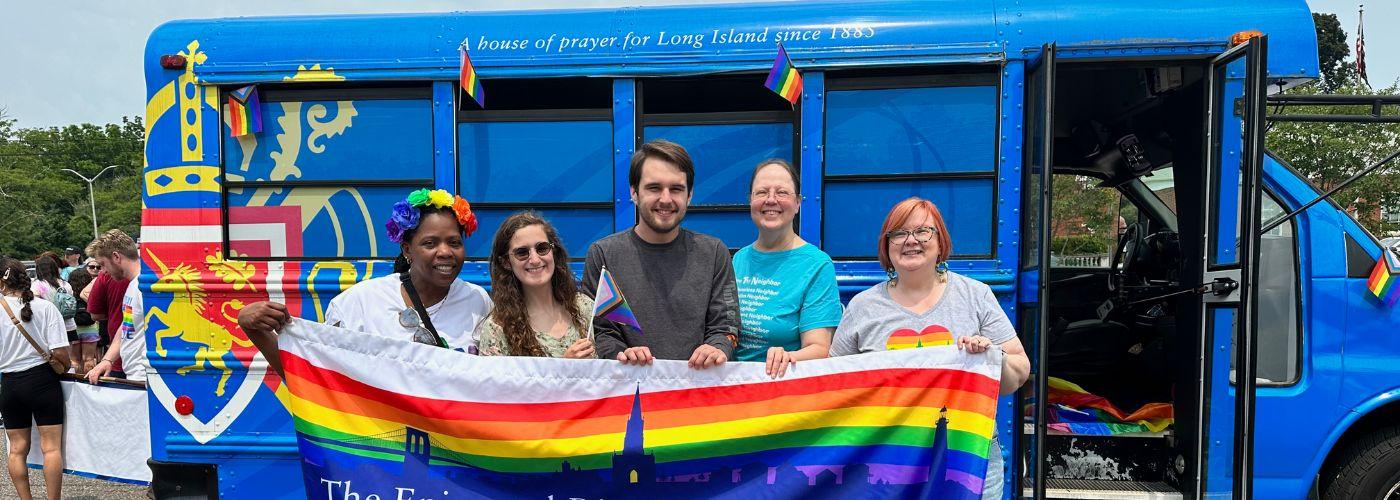 A group of people gathered outside of the Cathedral bus at a pride march
