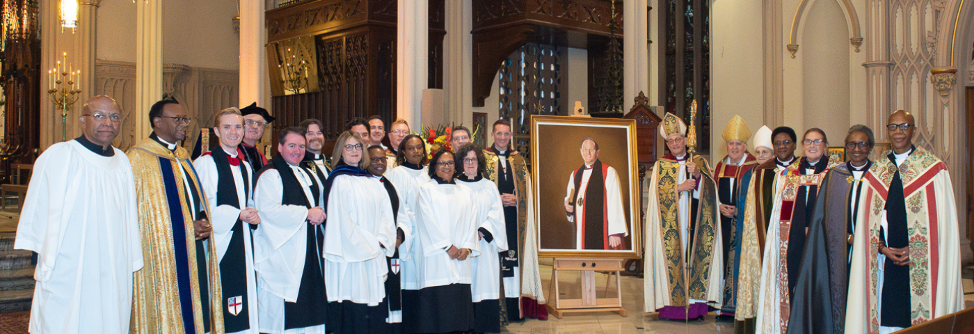 Clergy gathered around the portrait of Bishop Provenzano