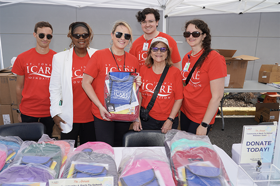 St. Johns ICARE Foundation group gathered in front of a backpack distribution table
