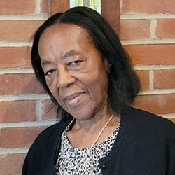 Headshot of Cynthia Stephens, head tilted to the left, wearing a white necklace, neutral look on her face.