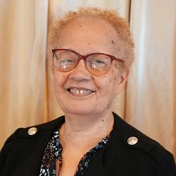 Headshot of Eileen Buckner, standing, wearing glasses, and smiling