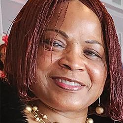 Headshot of Ilanye LongJohn: Red hair, wearing dangly ball earrings