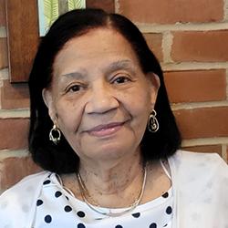 Headshot of Phillis Fibeuil, wearing a white polka-dot shirt with a white sweater