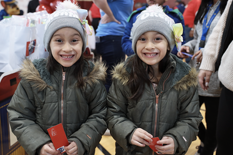 Two children stand with toys for Holiday Toy Drive