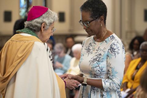 An altar guild member receives a blessing over her hands from Bishop Wolf